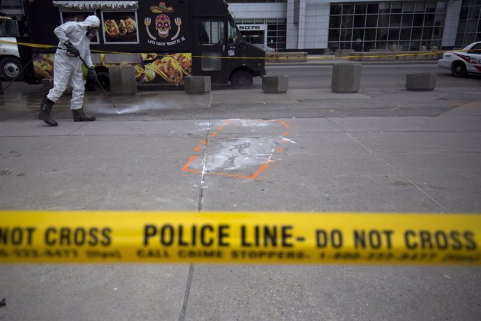 Archivo - Un hombre limpia tras el cordón policial que marcaba la escena del atropello realizado por Alek Minassian en Toronto.