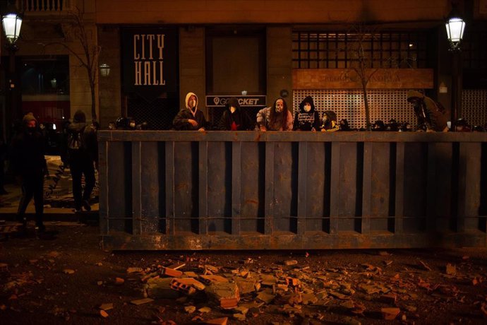 Manifestantes que apoyan a Pablo Hasel mueven mobiliario urbano durante los disturbios en Barcelona (España), a 17 de febrero de 2021.