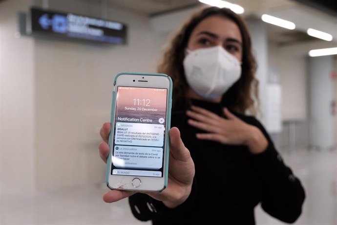 Archivo - Una chica muestra el SMS en su teléfono móvil que informa de su prueba negativa, en el aeropuerto de Palma.