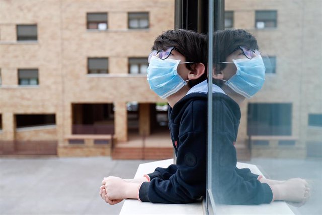Archivo - Un niño con una mascarilla se asoma a la ventana de su casa cuando queda tan solo una semana para que niños y preadolescentes puedan salir a la calle durante el confinamiento por el coronavirus, en Valdemoro/Madrid (España) a 20 de abril de 20