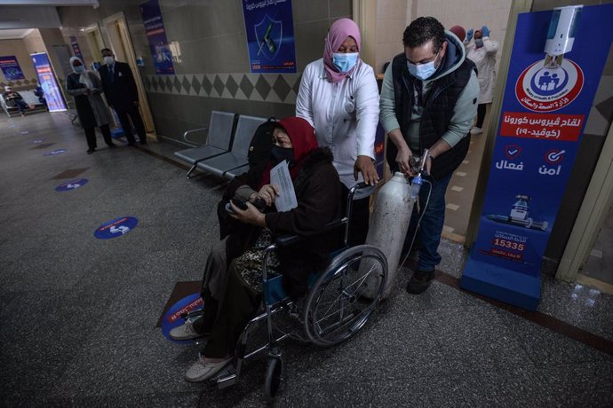 Unos sanitarios ayudan a una anciana a desplazarse para recibir la primera dosis de la vacuna de AstraZeneca contra el coronavirus en el centro medico Qattameya durante la primera jornada masiva de vacunación en Egipto.
