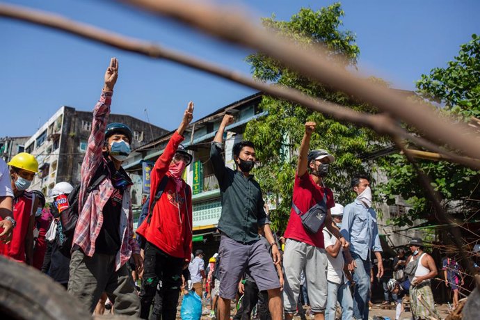 01 March 2021, Myanmar, Yangon: Protesters flash the three finger salute behind a barricade during clashes at a protest against the military coup and detention of civilian leaders in Myanmar. Photo: Aung Kyaw Htet/SOPA Images via ZUMA Wire/dpa