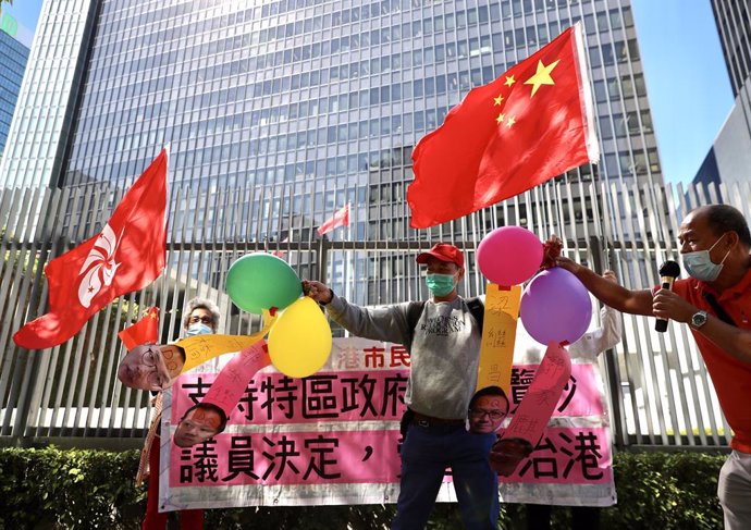 Archivo - 12 November 2020, China, Hong Kong: Pro-government members hold balloons with papers faces of the four ousted lawmakers as they celebrate outside the legislative council the resignation of pro-democratic legislators. 15 lawmakers resigned en m