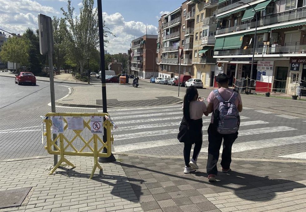 Archivo - Dos personas pasan junto a una valla de restricción de movilidad en el municipio de San Sebastián de los Reyes.