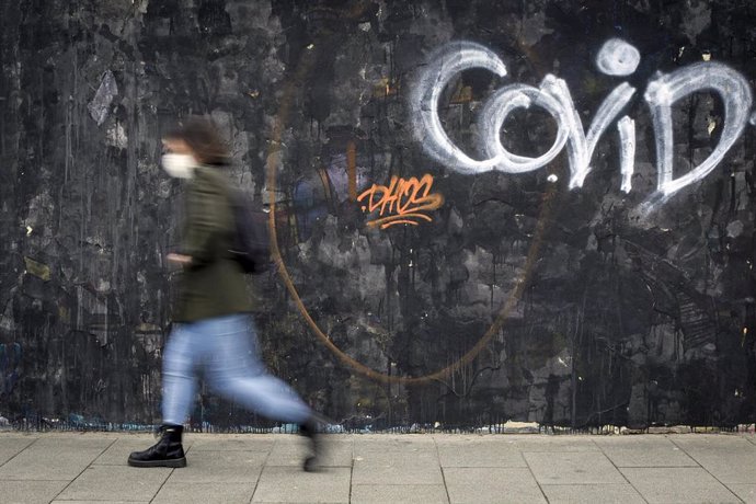 Una mujer pasa al lado de un grafitti del artista J.Warx en una vía de Valencia