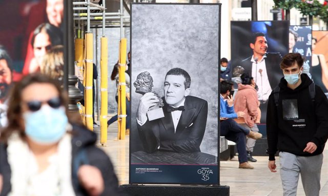 Varias personas pasean por calle Larios de Malaga entre una exposición sobre los premios Goya