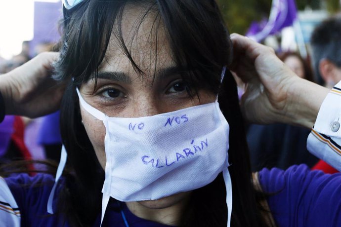 Archivo - Una mujer se coloca una mascarilla en la que se lee 'No nos callarán' durante la marcha por el Día Internacional de la Mujer en Málaga, (Andalucía, España), a 08 de marzo de 2020, foto de archivo