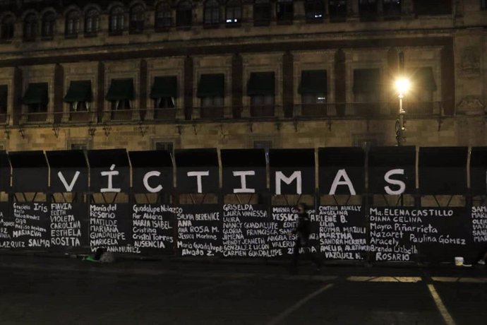 Homenaje a víctimas de violencia machista en la valla levantada en el Zócalo de Ciudad de México con motivo del Día de la Mujer