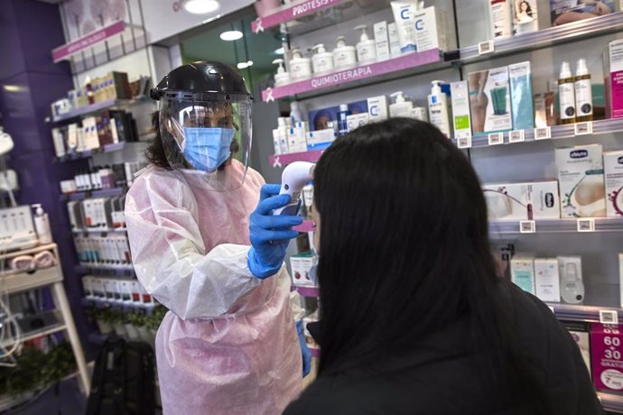 Una farmacéutica toma la temperatura a una mujer antes de realizarle un test de antígenos en la Farmacia Las Gemelas en Madrid (España), a 11 de febrero de 2021. El pasado miércoles 3 de febrero, Salud Pública comenzó a mandar SMS para que los ciudadano