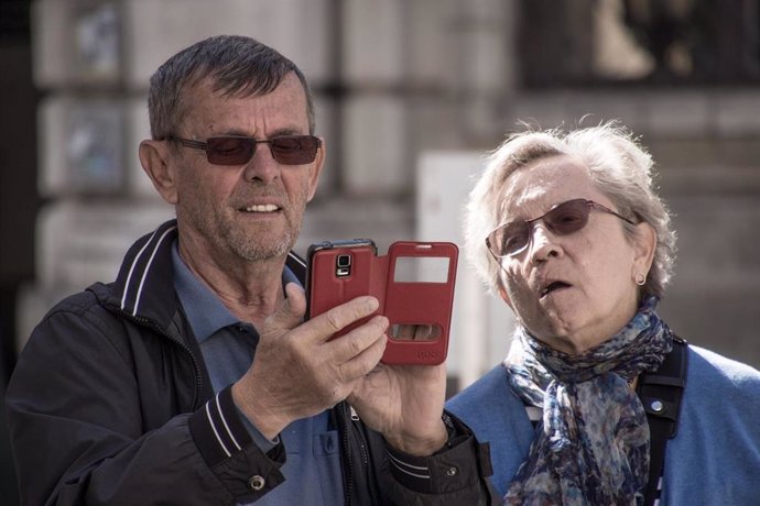 Dos ancianos observan un teléfono móvil