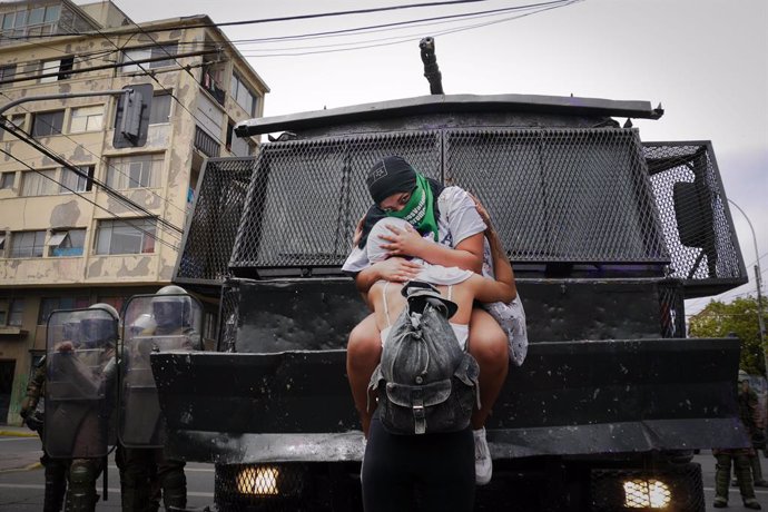 08 March 2021, Chile, Valparaíso: Two women embrace each other in front of a security force vehicle during a demonstration for women's rights on International Women's Day. Photo: Santiago Morales/Agencia Uno/dpa
