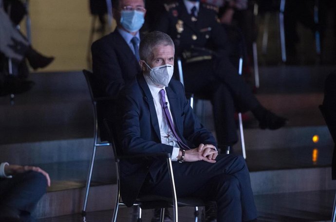 El ministro de Interior, Fernando Grande-Marlaska, sigue el acto por el Día de la Mujer con el comisario José Antonio Rodríguez sentado en segundo plano