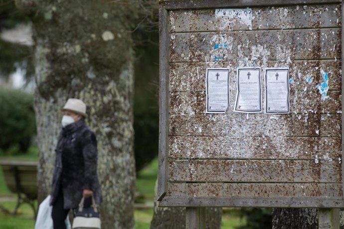 Una mujer pasa junto a un panel con esquelas en el municipio de Guitiriz (Lugo)