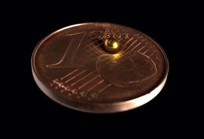 La bola de oro utilizada en comparación de tamaño con una moneda de 1 centavo. Según la teoría de la relatividad general de Einstein, toda masa dobla el espacio-tiempo