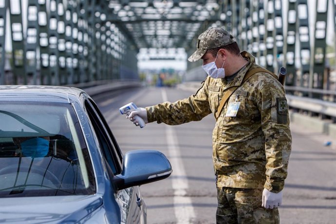 Archivo - 20 May 2020, Ukraine, Chop: A border guard personnel measures a driver's body temperature at the Tysa international automobile checkpoint on the Ukraine-Hungary border during the coronavirus quarantine. Photo: -/Ukrinform/dpa