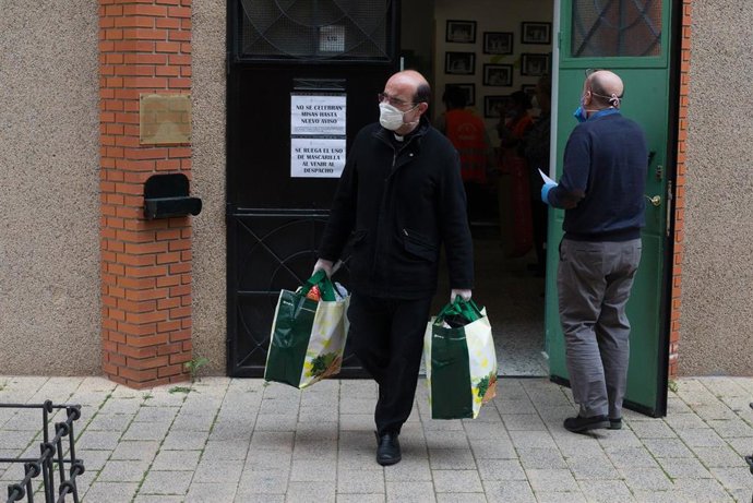 Archivo - Un sacerdote ayuda a recoger alimentos para llevarlos al almacén de la Parroquia de San Juan de Dios, en Vallecas, durante la pandemia.
