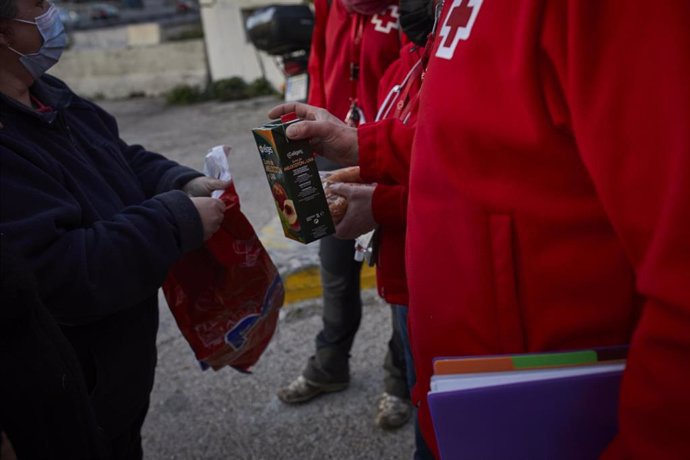 Varios trabajadores de Cruz Roja ofrecen comida a una mujer en Madrid.