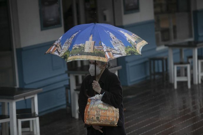 Archivo - Una mujer camina bajo su paraguas durante un día lluvioso y con rachas de viento en la provincia. En Sevilla (Andalucía, España), a 09 de febrero de 2021.