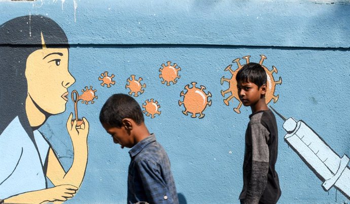 05 March 2021, India, Mumbai: Boys walk past a mural raising awareness about coronavirus in Mumbai. Photo: Ashish Vaishnav/SOPA Images via ZUMA Wire/dpa