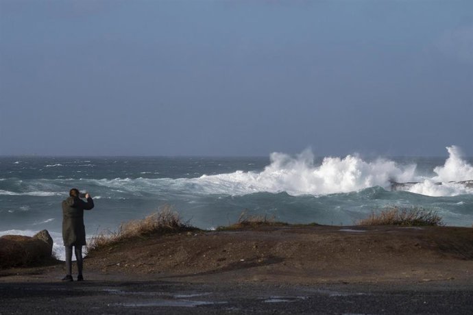 Archivo - Una persona graba el oleaje.