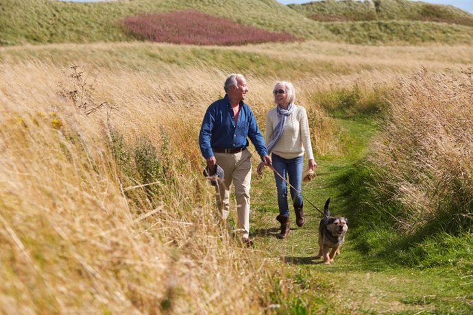 Archivo - Senior Couple Taking Dog For Walk In Countryside