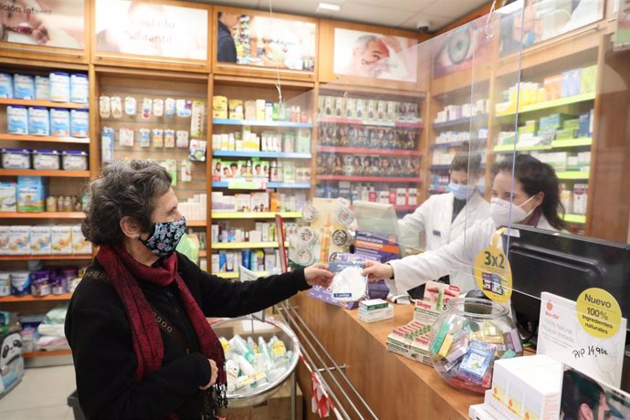 Archivo - Una anciana recoge una mascarilla FFP2 en la farmacia situada en la C/Tucán (Carabanchel), en Madrid (España), a 4 de febrero de 2021. Los mayores de 65 años de la Comunidad de Madrid pueden recoger a partir de hoy la primera de las dos mascar