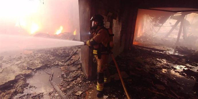 Un bombero trabaja en la extinción de un incendio declarado en una nave del polígono La Polvorista, en Molina de Segura