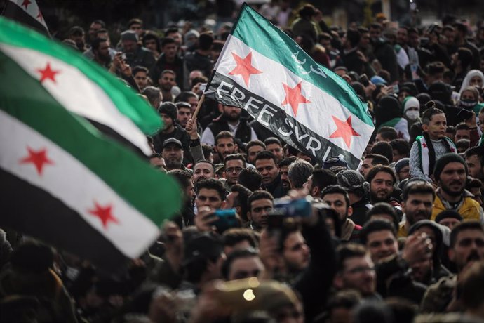 15 March 2021, Syria, Idlib City: People wave flags of the Syrian opposition during a mass demonstration held to mark the tenth anniversary of the start of the Syrian civil war. Photo: Anas Alkharboutli/dpa