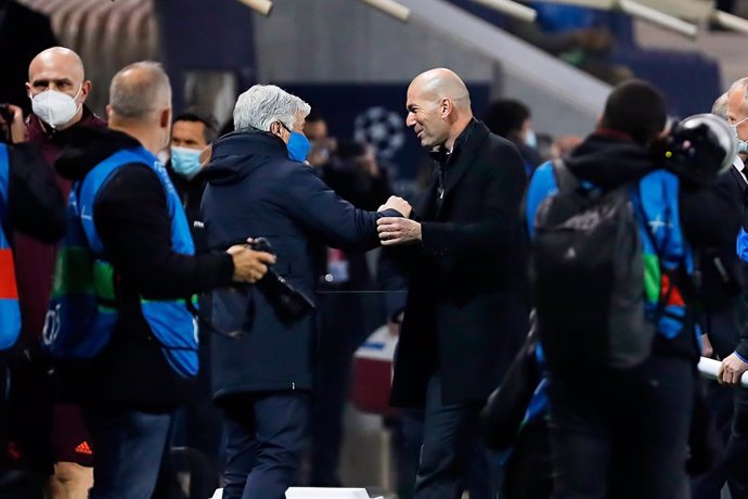 24 February 2021, Italy, Bergamo: Real Madrid head coach Zinedine Zidane (R) and Atalanta head coach Gian Piero Gasperini greet each other during the UEFAChampions League round of 16 first leg soccer match between Real Madrid and Atalanta BC at Gewiss 