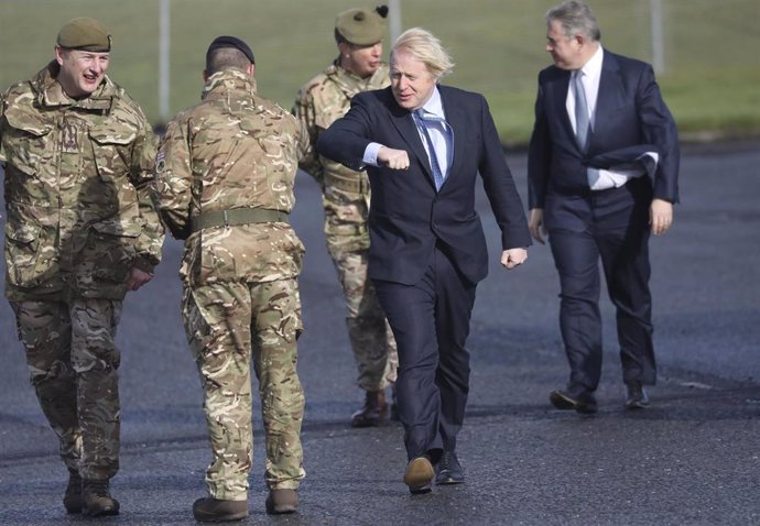 12 March 2021, United Kingdom, Belfast: UKPrime Minister Boris Johnson greets troops alongside Northern Ireland Secretary Brandon Lewis (R) and Brigadier Chris Davies, Commander 38 Irish Brigade (L), during a visit to Joint Helicopter Command Flying St