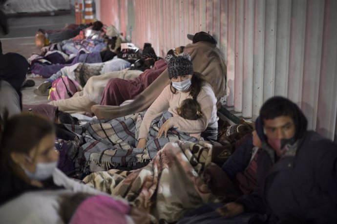 19 February 2021, Mexico, Tijuana: Central American and Mexican migrants sleep on the esplanade of the National Institute of Migration near the El Chaparral border crossing, waiting for US authorities to let them enter to begin their humanitarian asylum