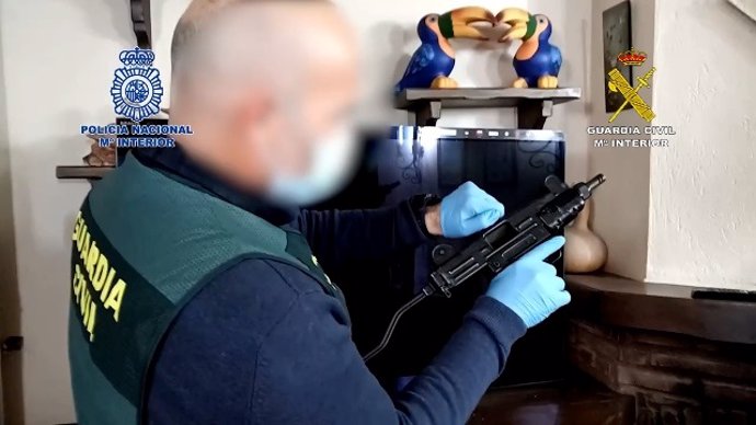 Agente de la Guardia Civil con una de las armas intervenidas en una operación contra el tráfico de drogas realizada en Málaga