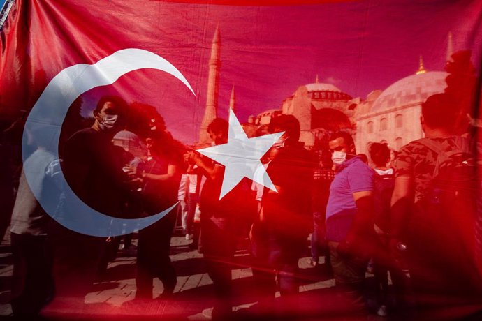 Archivo - 10 July 2020, Turkey, Istanbul: People celebrate behind a Turkish national flag in front of Hagia Sophia, after a court decision to revoke the Hagia Sophia's status as a museum, paving the way for it to be turned into a mosque. Turkish Preside