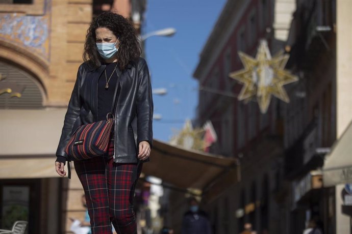 Archivo - Una mujer con mascarilla camina por la plaza de San Francisco, al fondo las luces del alumbrado de navidad de la calle Sierpes, en Sevilla (Andalucía, España), a 20 de noviembre de 2020.