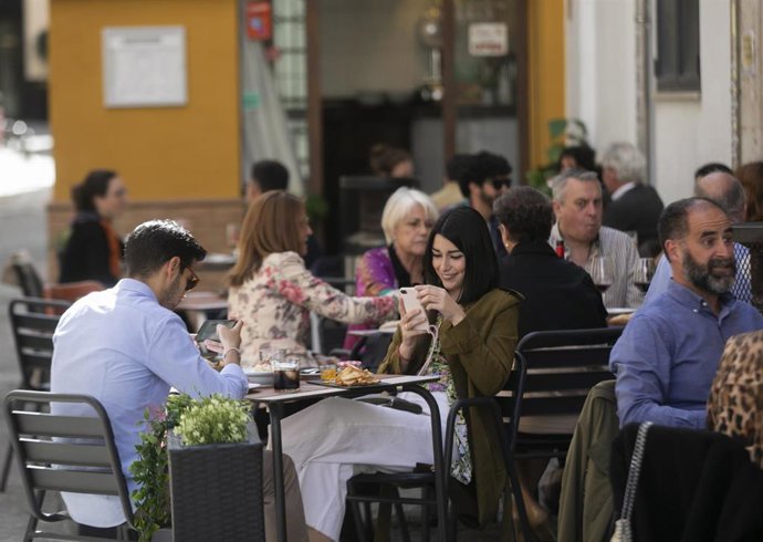 Personas en la terraza de un bar en Sevilla (Andalucía, España)