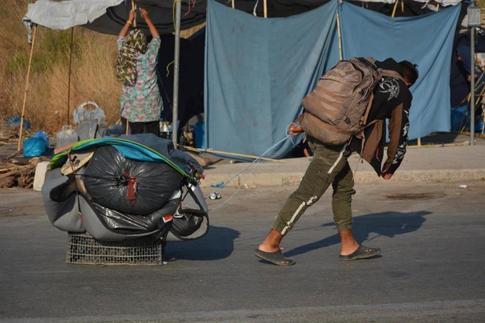 Archivo - Un migrante llevando sus pertenencias en la isla de Lesbos tras el incendio del campamento de Moria