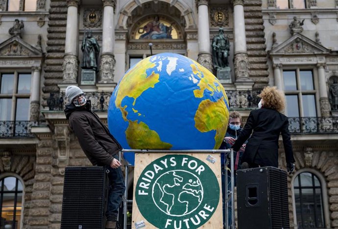 Archivo - 11 December 2020, Hamburg: Activists of "Fridays for Future" carry a ballon in the shape of the earth while building a so-called "Gallery of Failure" on the Hamburg City Hall Market on the nationwide day of action to commemorate the 1.5-degree