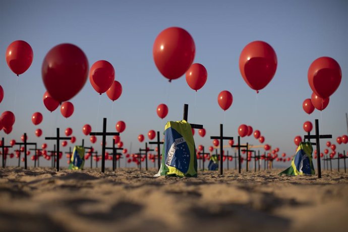 Archivo - 08 August 2020, Brazil, Rio de Janeiro: Brazilian flags and red balloons are seen attached to 100 crosses, by the Rio de Paz NGO, at the Copacabana beach, in memory of victims who died of coronavirus, after COVID-19 related deaths topped 100,0