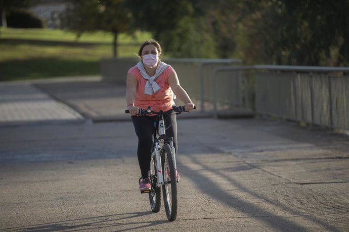 Archivo - Una mujer con mascarilla pasea en bicicleta. 