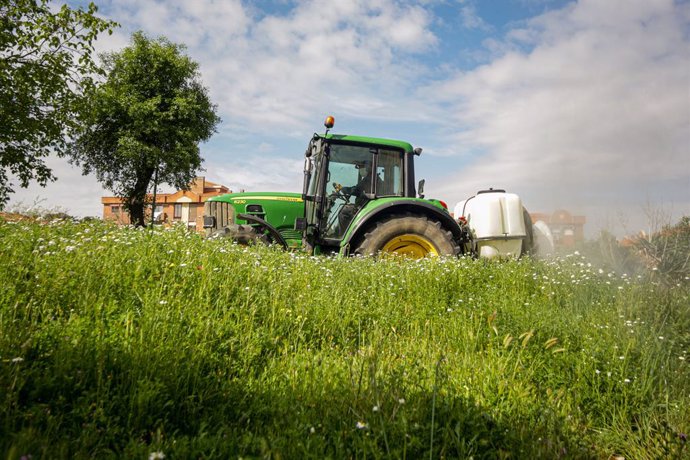 Archivo - Un agricultor montado en su tractor desinfecta las inmediaciones de Aranjuez