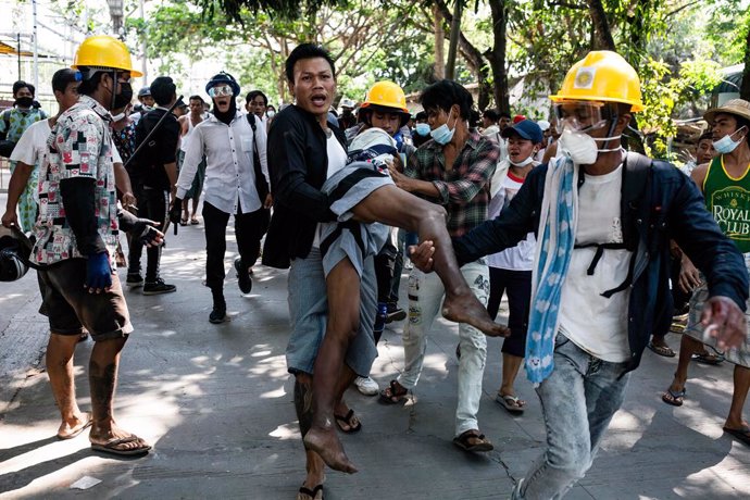 19 March 2021, Myanmar, Yangon: Demonstrators carry a wounded man during clashes at a protest against the military coup and the detention of civilian leaders. Photo: Aung Kyaw Htet/SOPA Images via ZUMA Wire/dpa