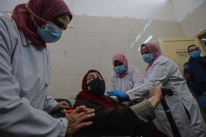 04 March 2021, Egypt, Cairo: Health workers prepare an elderly woman to receive a dose of AstraZeneca's COVID-19 vaccine at Qattameya's Medical center. Starting from today, Egypt is including the elderly and people with chronic diseases in the coronavir