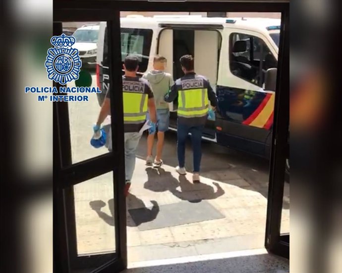 Dos agentes de la Policía Nacional conducen al detenido al interior de un furgón policial