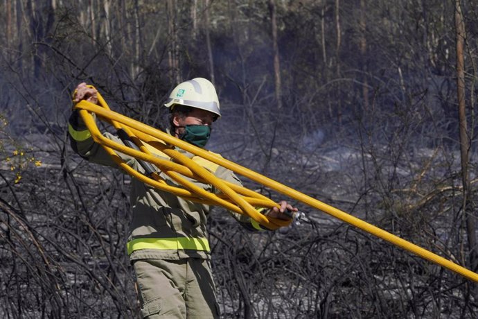 Un bombero apaga el incendio forestal en la parroquia de Figueriras en Santiago de Compostela, A Coruña, Galicia (España), a 20 de marzo de 2021. El incendio, ya estabilizado, se originó en torno a las 6 de la madrugada y este mediodía ya afectaba a una