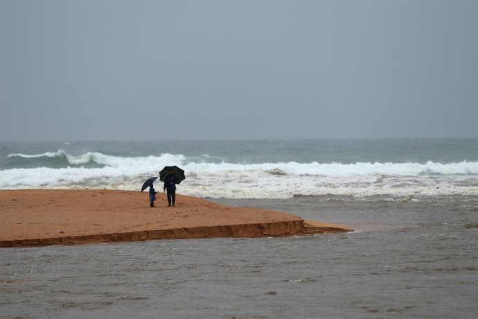 20 March 2021, Australia, Sydney: People stand on the edge of Narrabeen Lagoon and Narrabeen Beach. After days of heavy rain showers, the Bureau of Meteorology issued a severe weather warning for people in the state of New South Wales and warned of pote