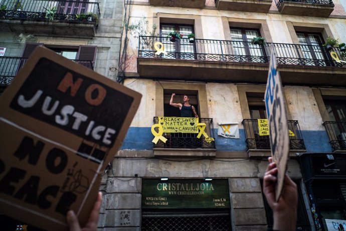Archivo - Un hombre se asoma a su balcón del que cuelga una pancarta en la que se lee 'Black Lives Matter' durante una concentración en Plaza de Sant Jaume de Barcelona contra el racismo 'Las vidas negras importan' organizada por  la Comunidad Negra Afr