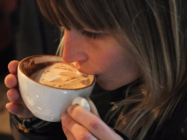 Archivo - Una mujer disfruta de una taza de café con leche