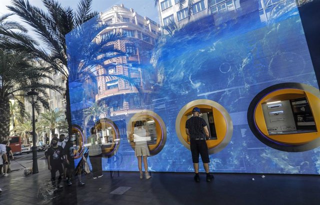 Archivo - Personas sacando dinero en los cajeros del edificio de la sede de Caixabank, en Valencia, Comunidad Valenciana (España).