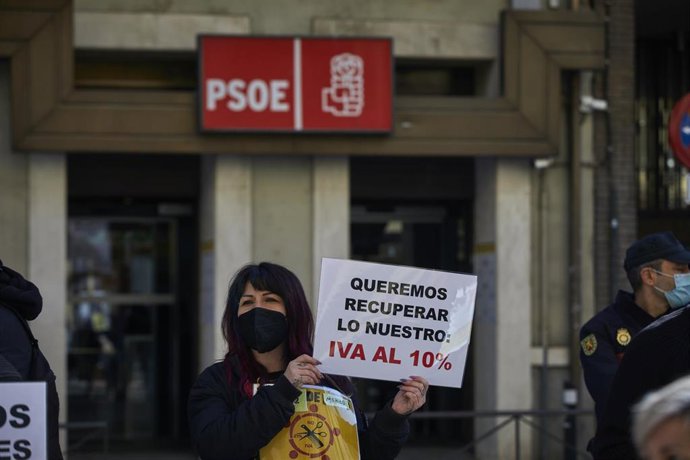 Una profesional del sector de la peluquería y estética se concentra con una pancarta que pide la bajada del IVA al 10% frente a la sede del PSOE, en Madrid (España).