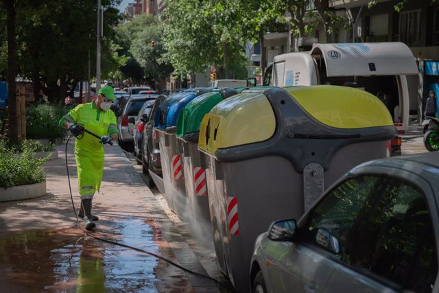 Archivo - Arxiu - Un operari de neteja del servei municipal desinfecta un contenidor groc d'escombraries a Barcelona.